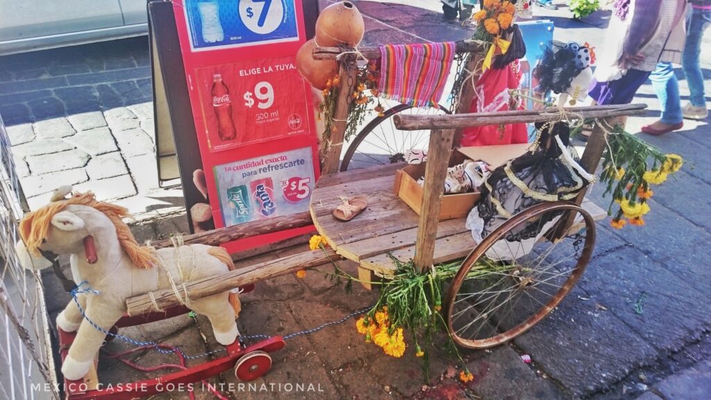 a child's ofrenda made on a small go cart pulled by a toy horse