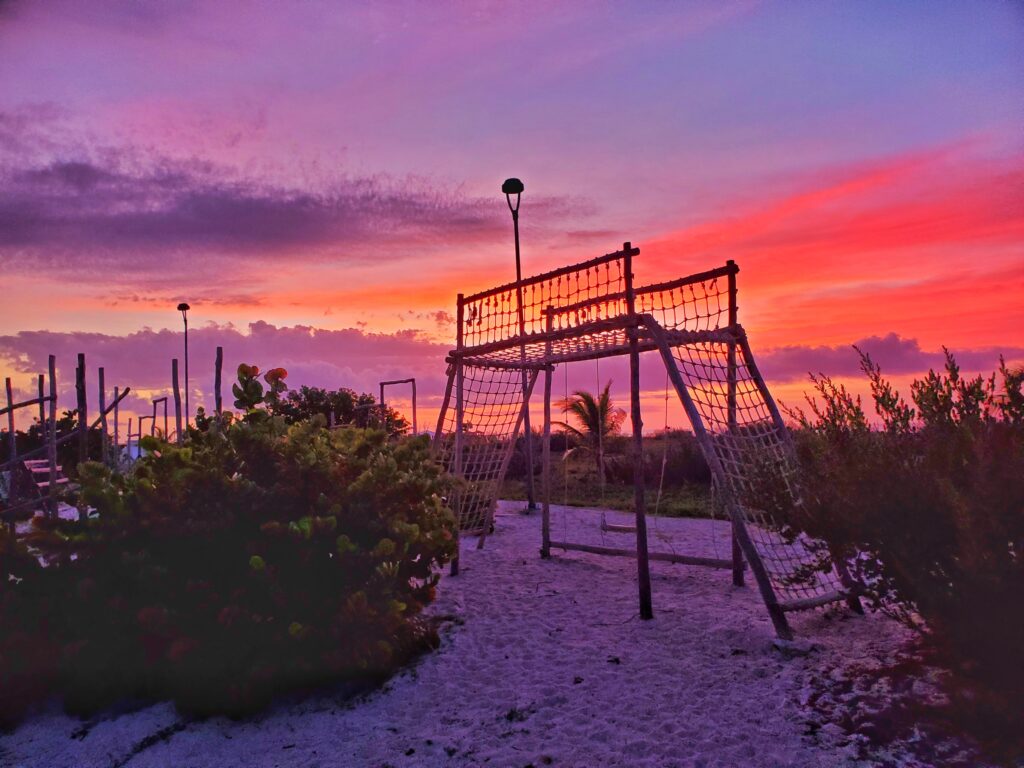 wooden net playground on beach at sunset. sky is pink and purple