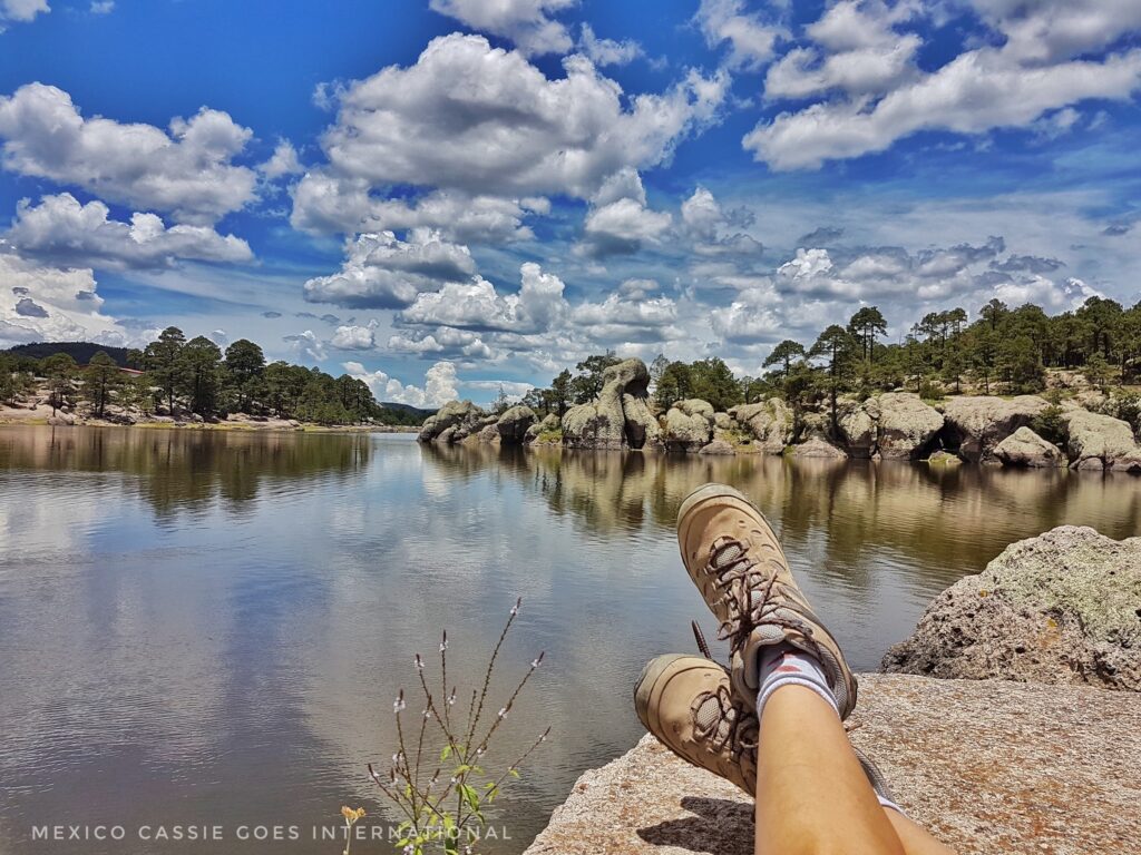 pair of feet on a rock in front of a calm lake