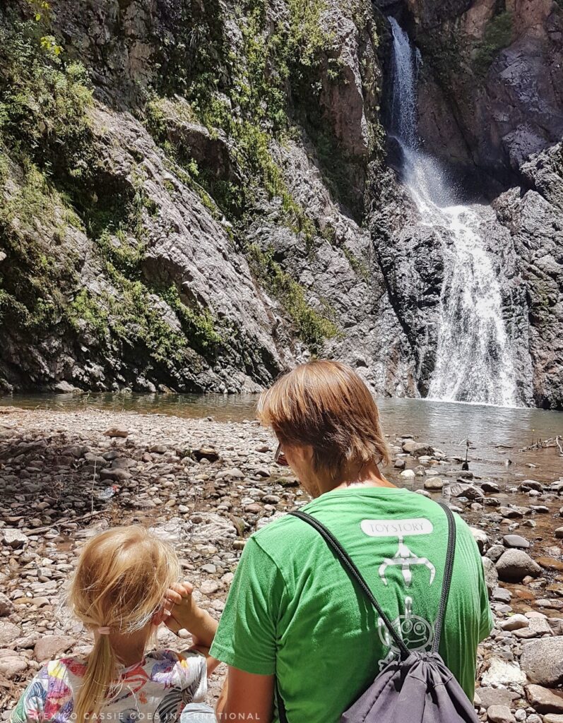 man and child sitting in front of small waterfall