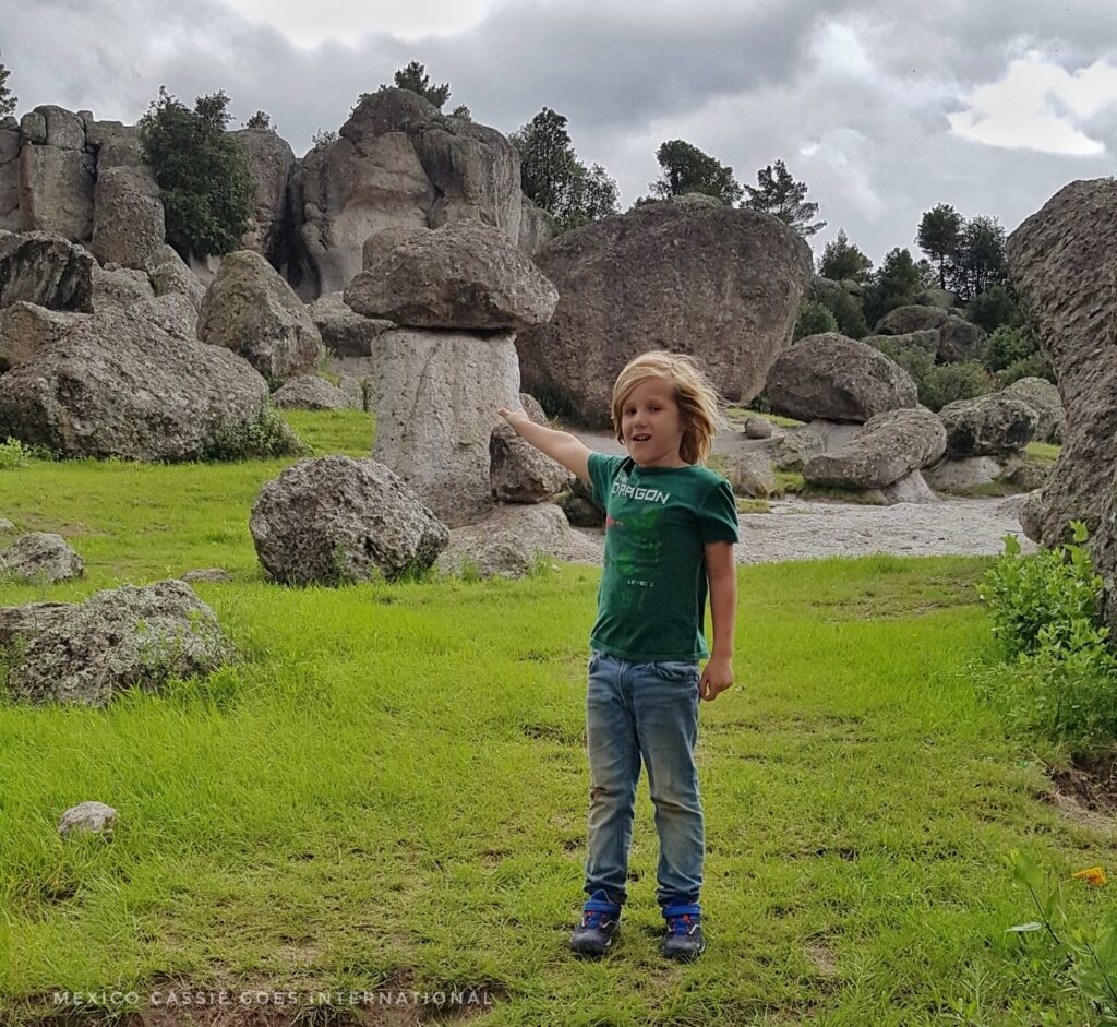 kid in green tshirt pointing at a rock shaped like a mushroom