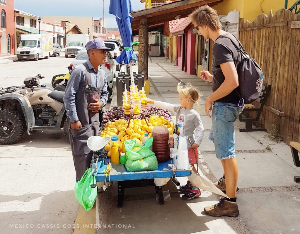 child and man buying fruit in cups from a man with a stall