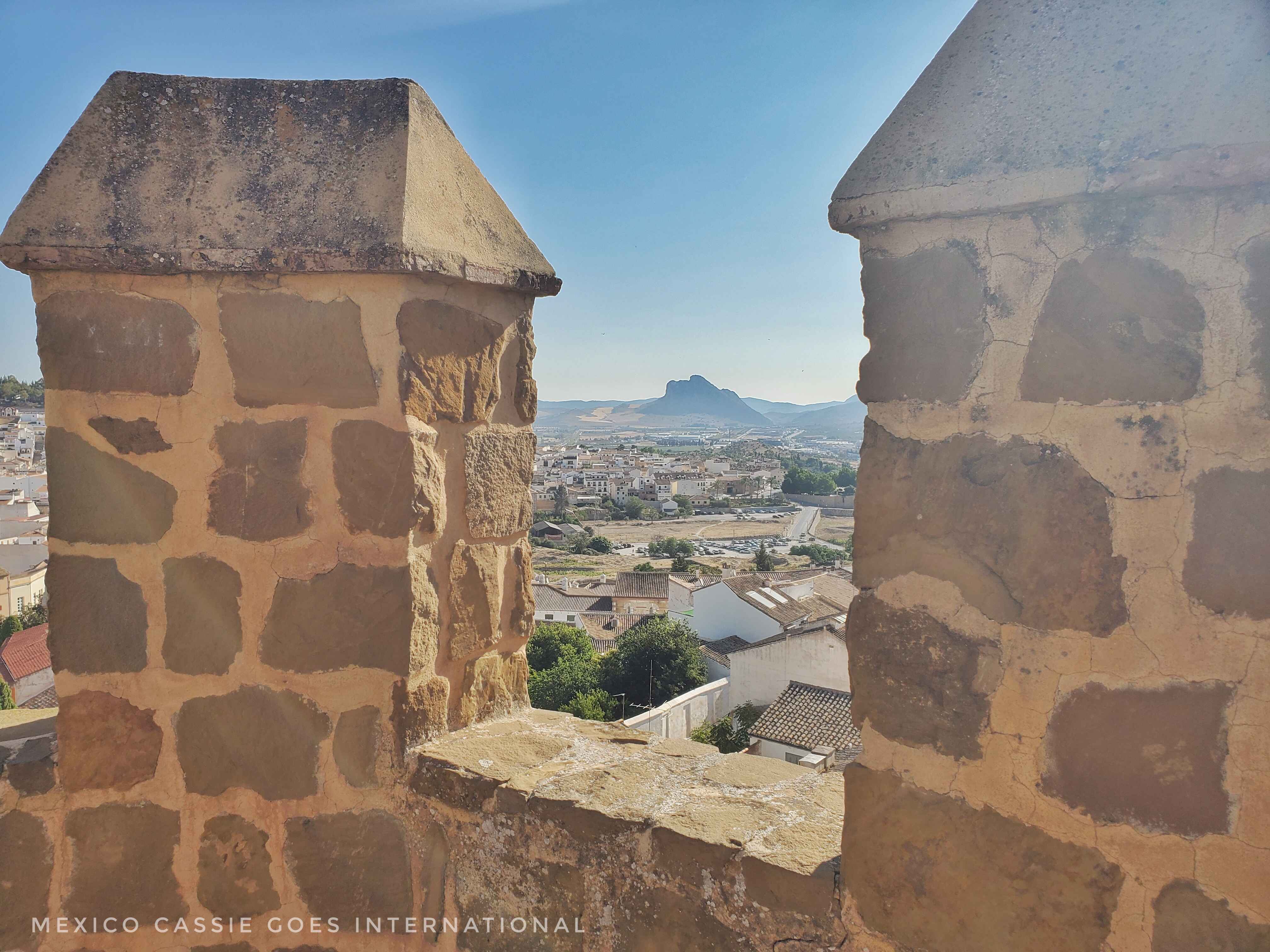 view of city of Antequera and prone face (peña de enamorados) from between battlements of alcazaba
