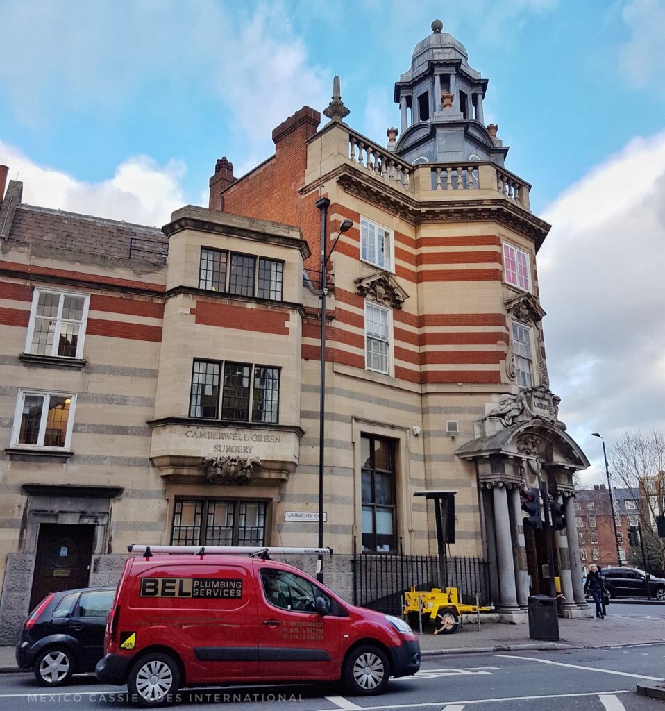 3 storey red and white brick building with grey domed tower on right hand side. red van in front
