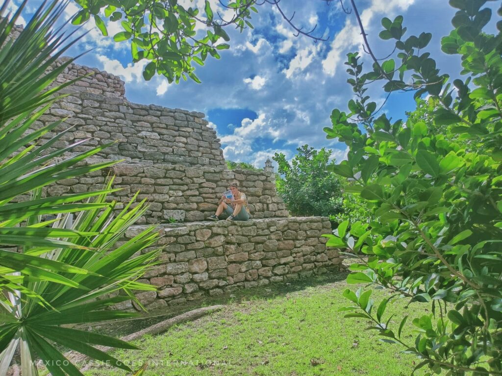 steps of a pyramid through the trees. cassie sitting on first step reading a book