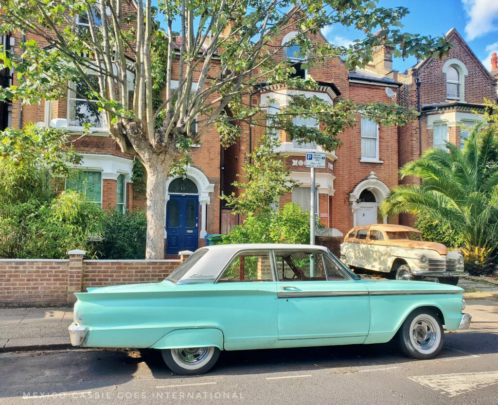 old mint green car outside red brick house