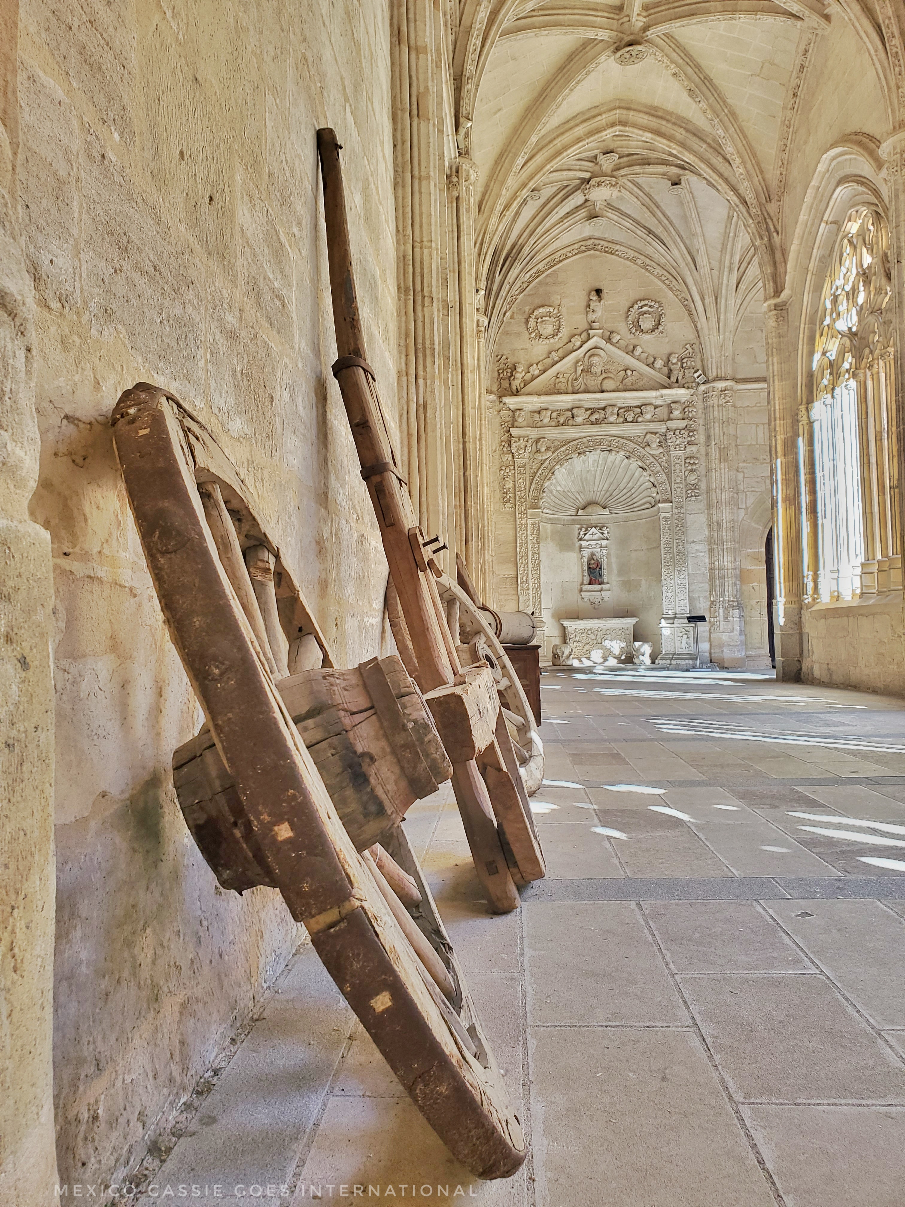 old wagon wheels lined up against wall of cathedral