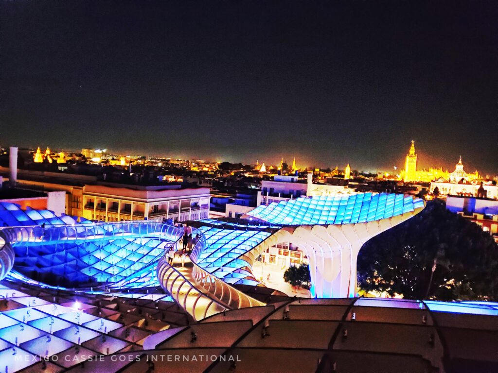 las setas by night - lit up blue with Seville skyline lit up against night sky behind