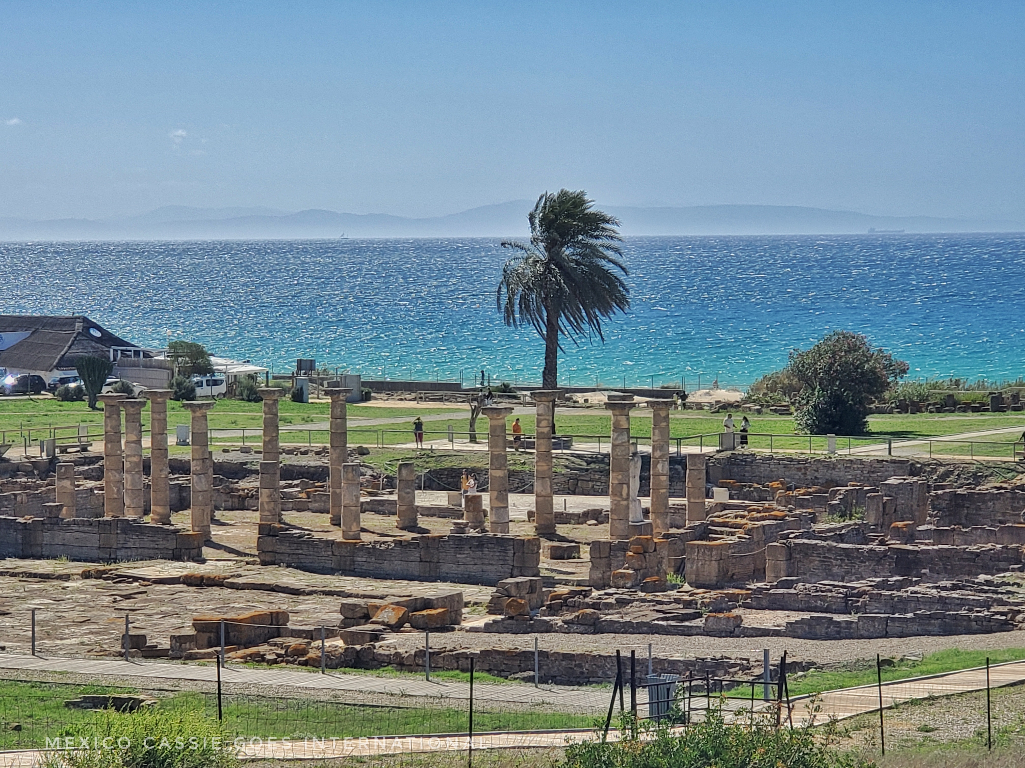 view of roman ruins (columns) in front of very blue ocean