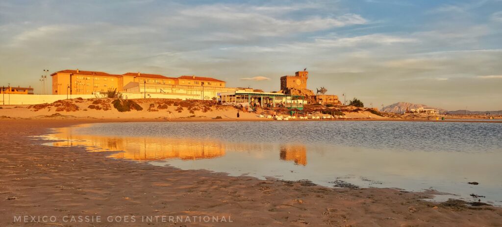 view of tarifa at sunset from beach with reflection of buildings in water