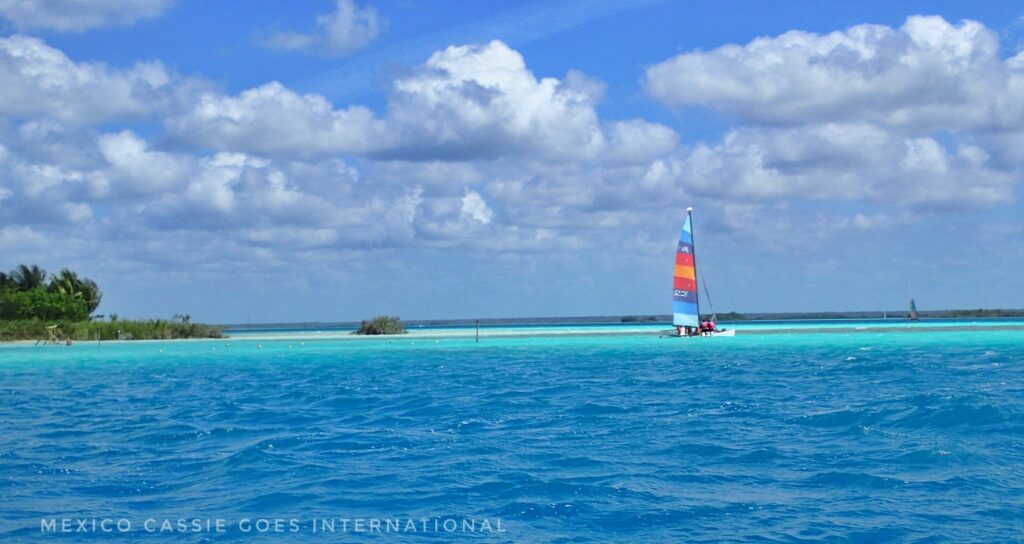 different shades of blue water - sailing boat in distance
