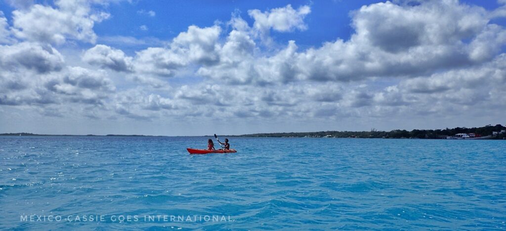 red kayak with two people in it on very blue water