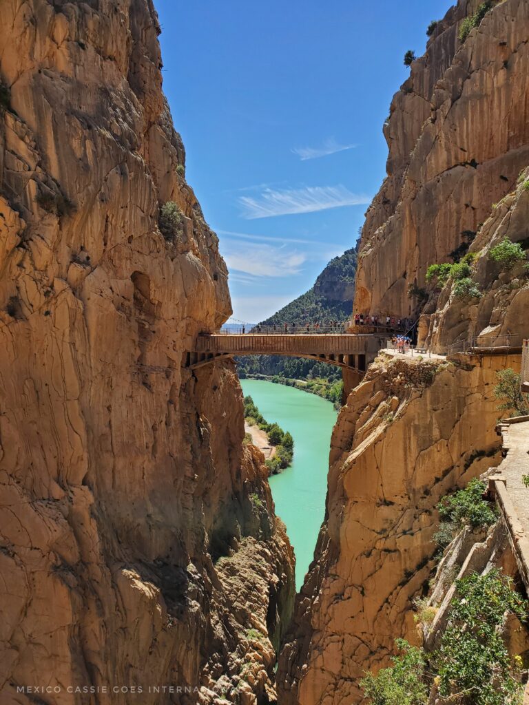 view of a bridge over a green lake between steep gorge walls on caminito del rey