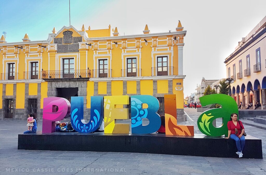 brightly coloured PUEBLA letters. yellow building in background