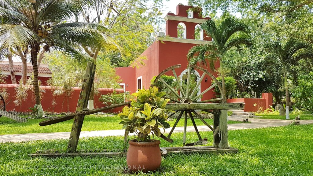 red hacienda building with wooden wheel in front