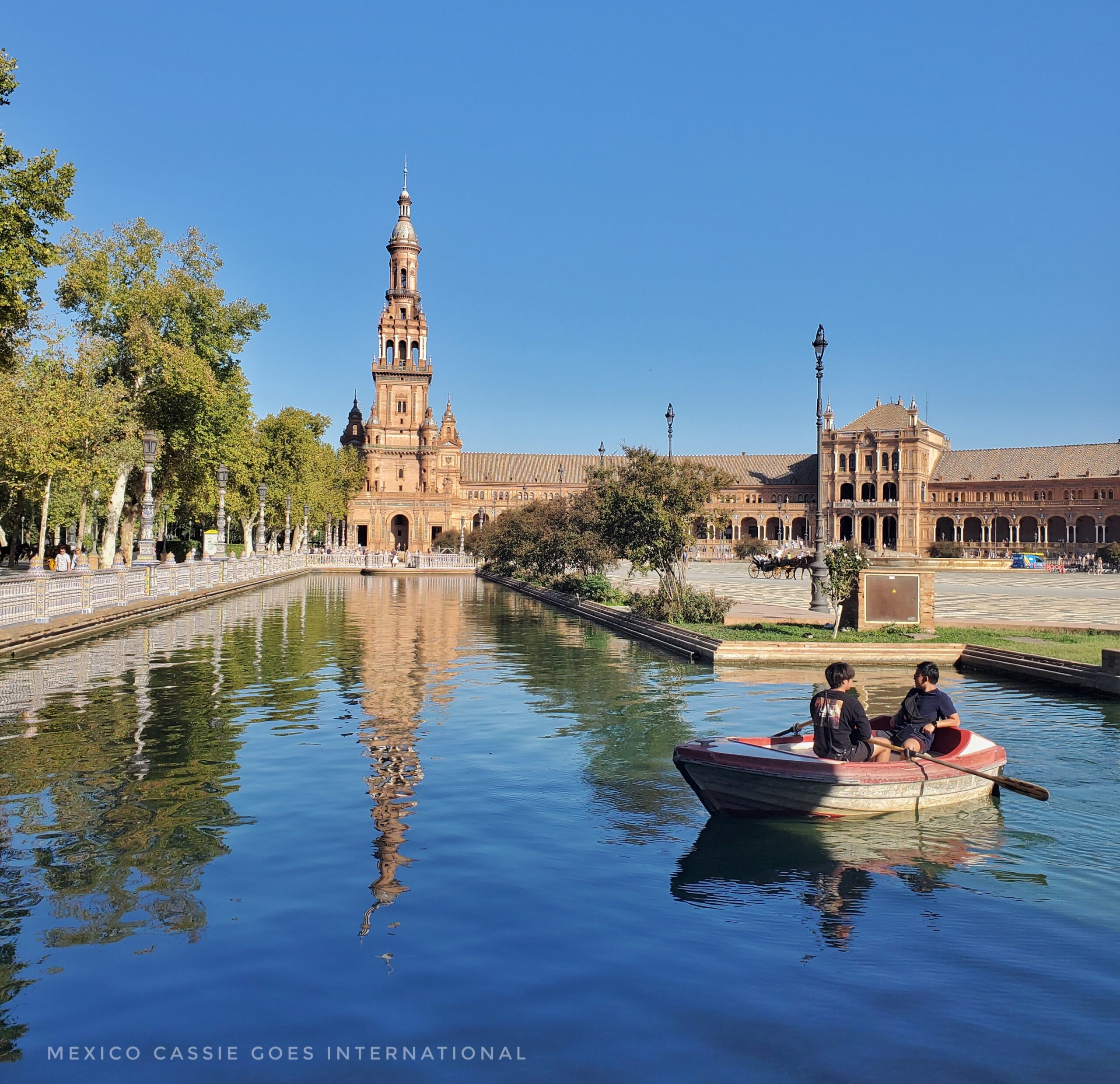 view of plaza de españa - rowing boat on water and tower reflected into clear water