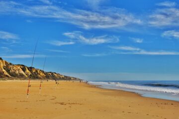 wide empty beach - fishing rods uprights in sand