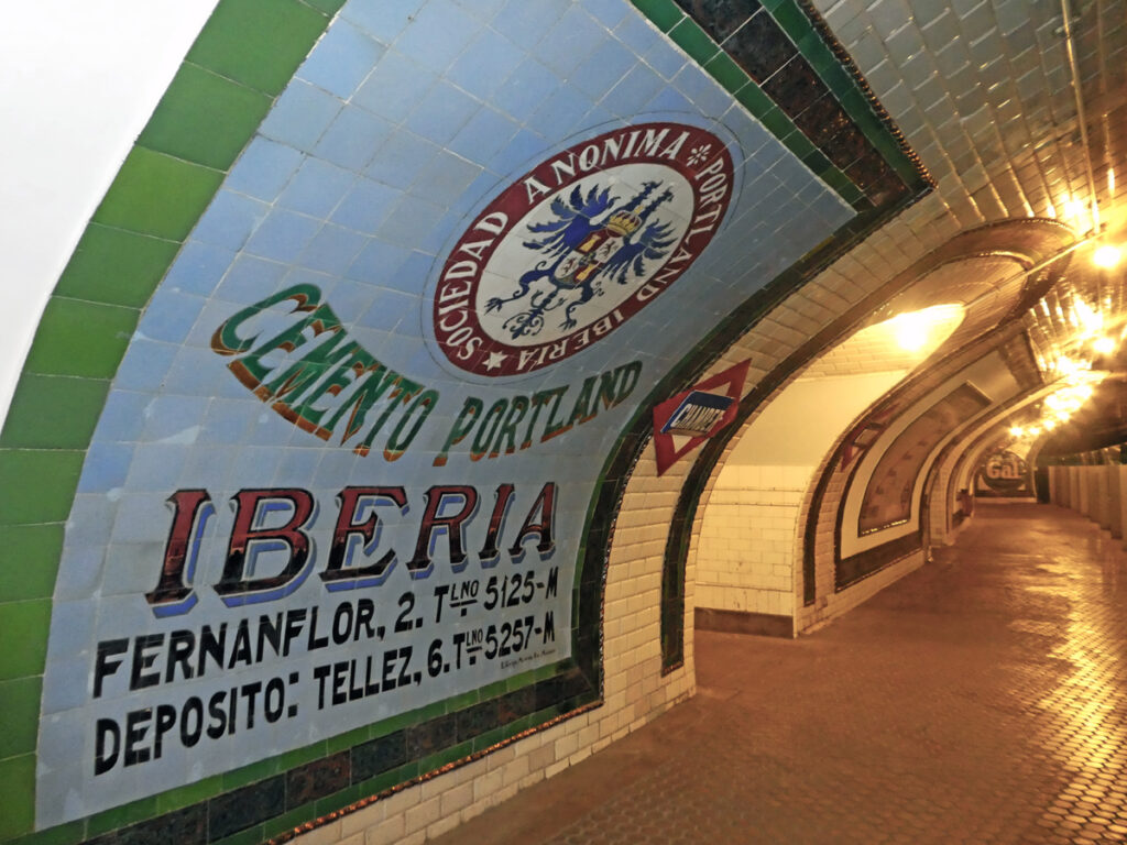 curved metro wall with adverts in the tiles - closest says "Iberia"