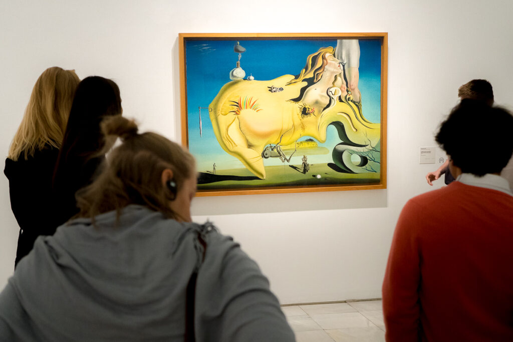 people looking at a dali on the wall of a gallery