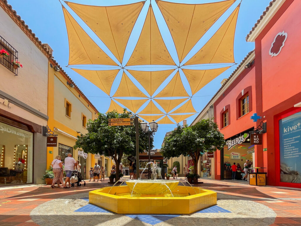 plaza with yellow fountain in middle and yellow shade covers over the plaza