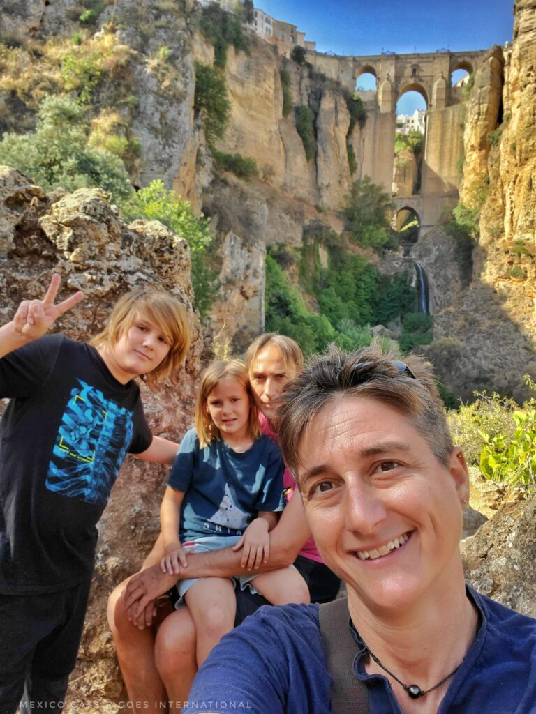 family of 2 adults and 2 kids in foreground, puente nuevo in Ronda behind