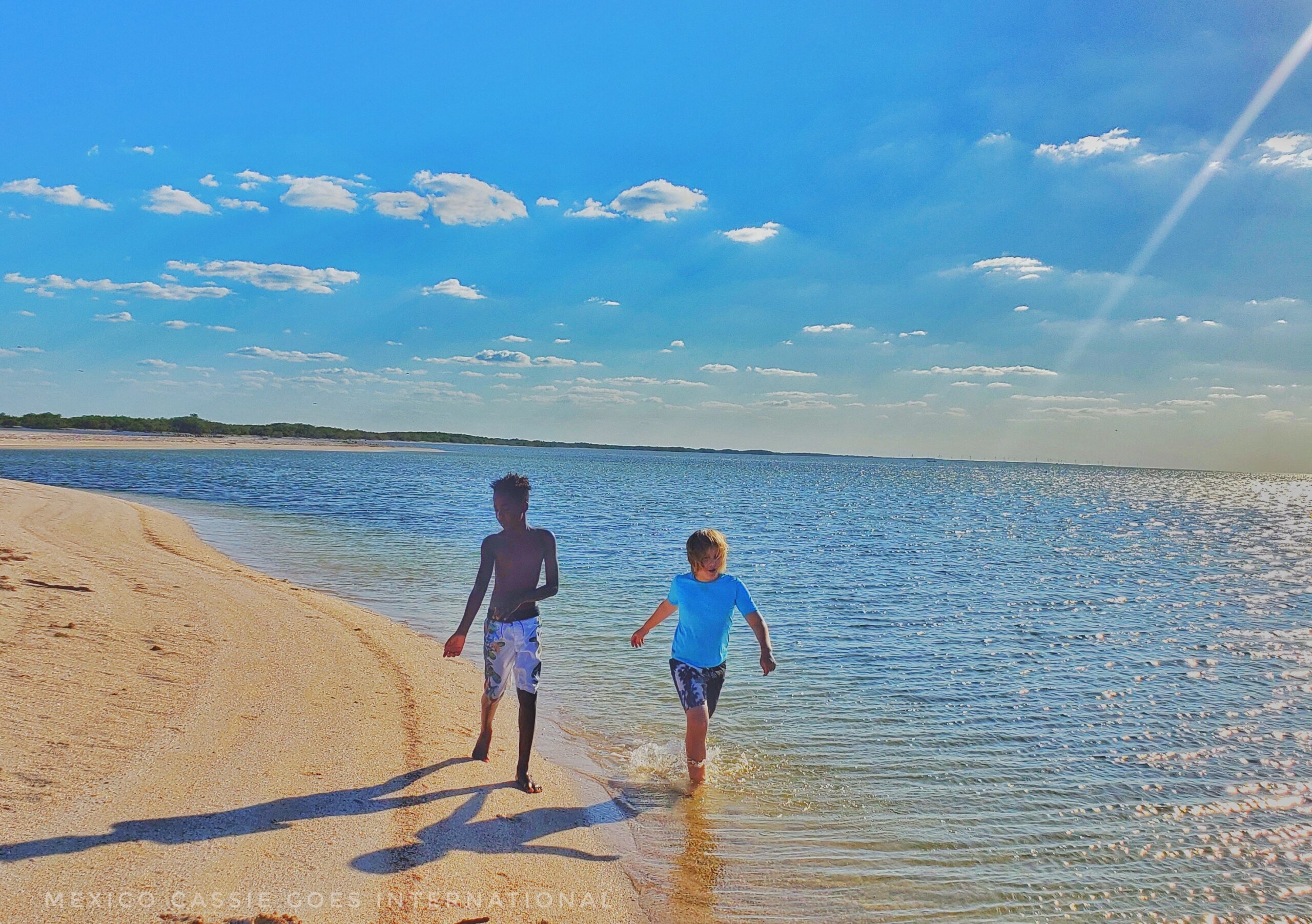 two boys walk along shore of very calm gulf beach
