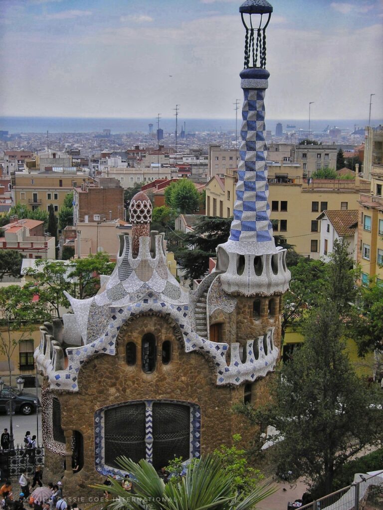 view of a Gaudi house - brick with white pointed roof and blue and white tall chimney