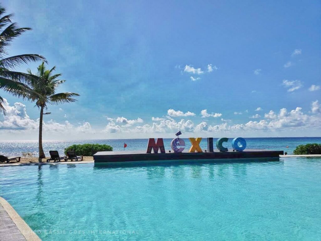 bright clear pool with large MÉXICO letters at ne end, ocean and sky behind