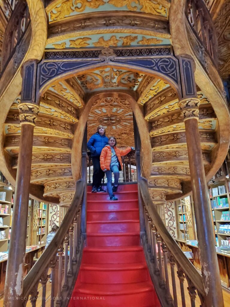 2 kids standing on a red staircase in a bookshop - single stairs going into double steps up