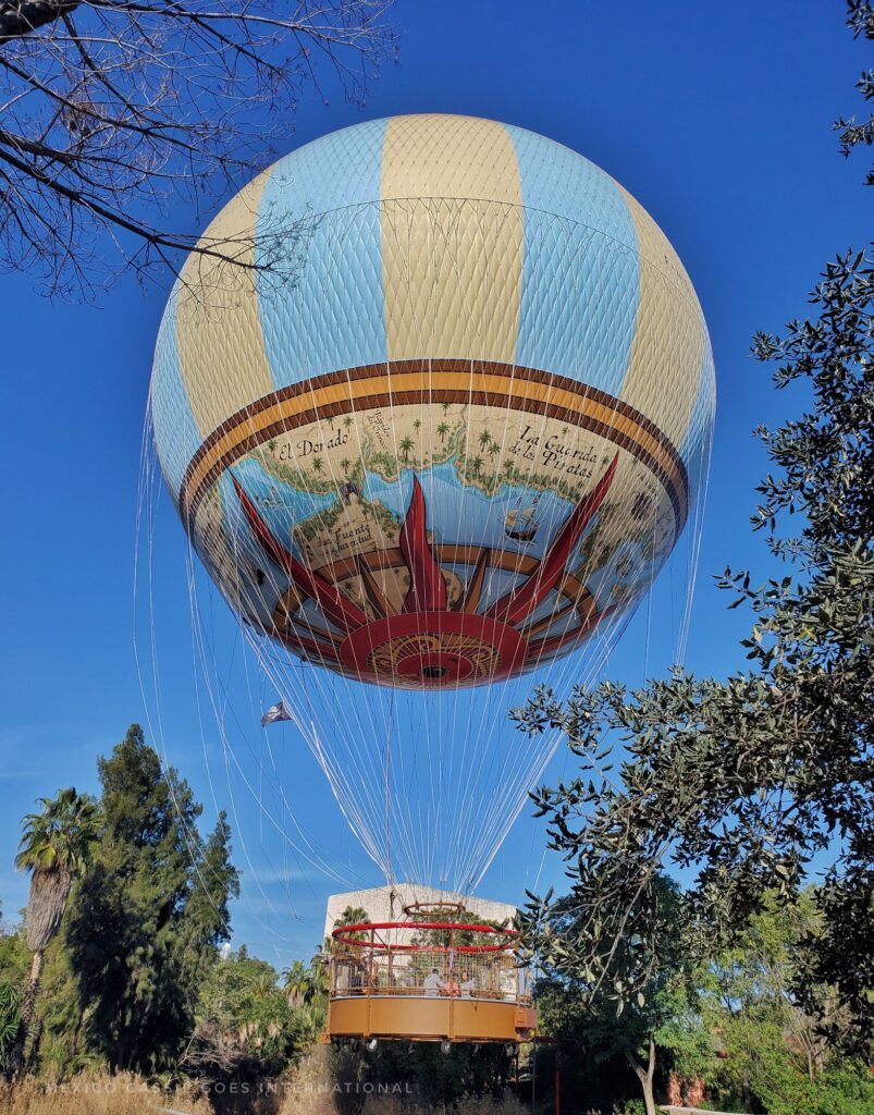 view of a yellow and blue hot airballoon with large basket as it lands