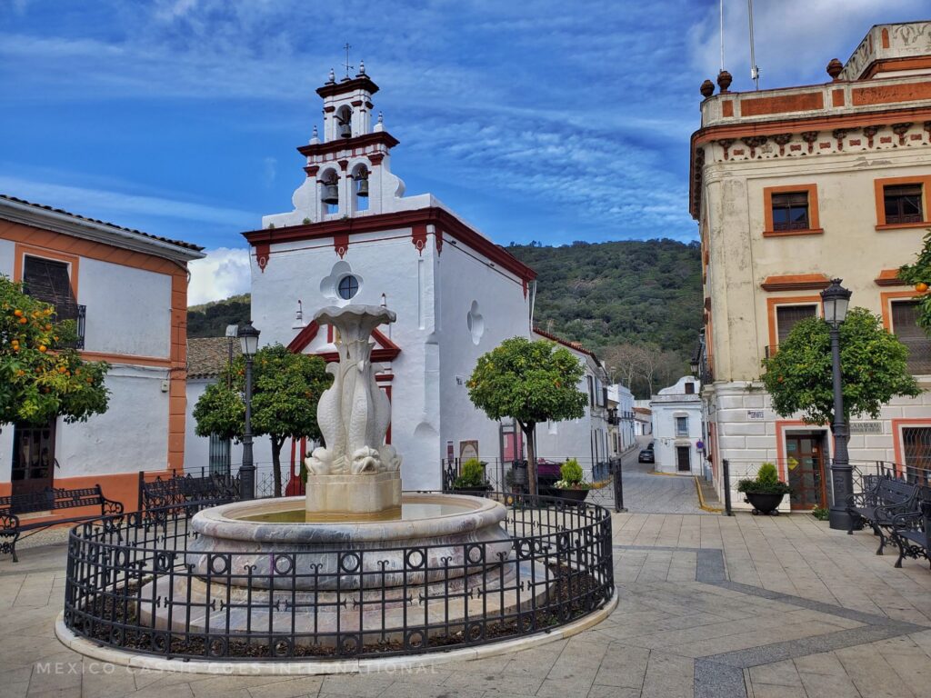 sleepy town plaza - fountain surrounded by small railing, white church, no people