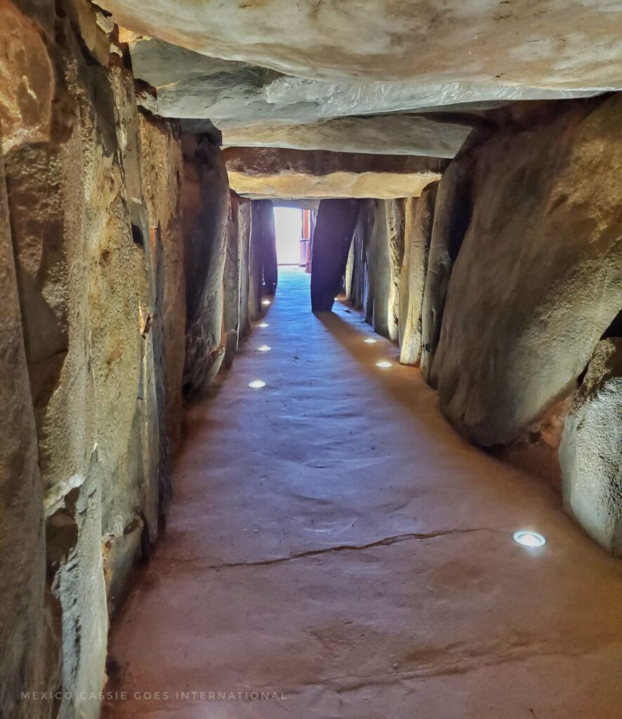 inside of a dolmen - lit path with monolith slabs on either side and over the top