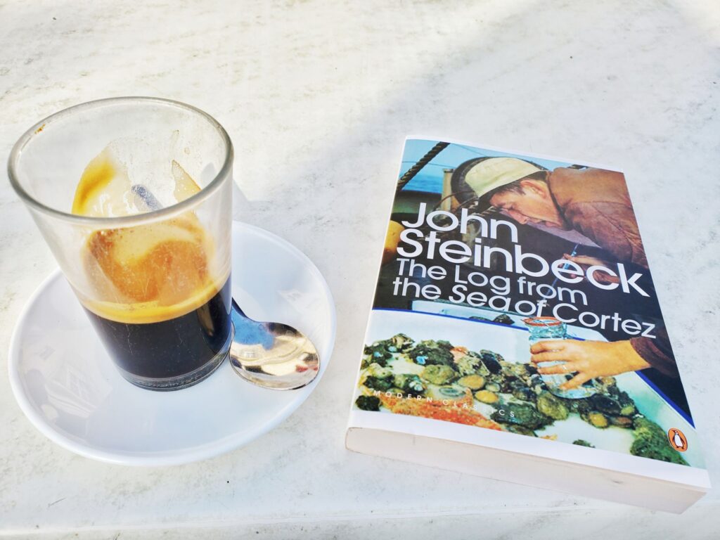 spanish cafe solo (thick coffee in a glass on a saucer) John Steinbeck novel "Sea of Cortez" next to it
