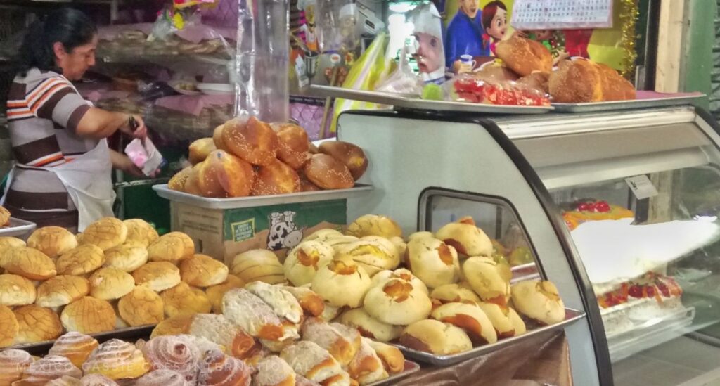 a bakery shot - lots of different types of bread, women in striped top in background