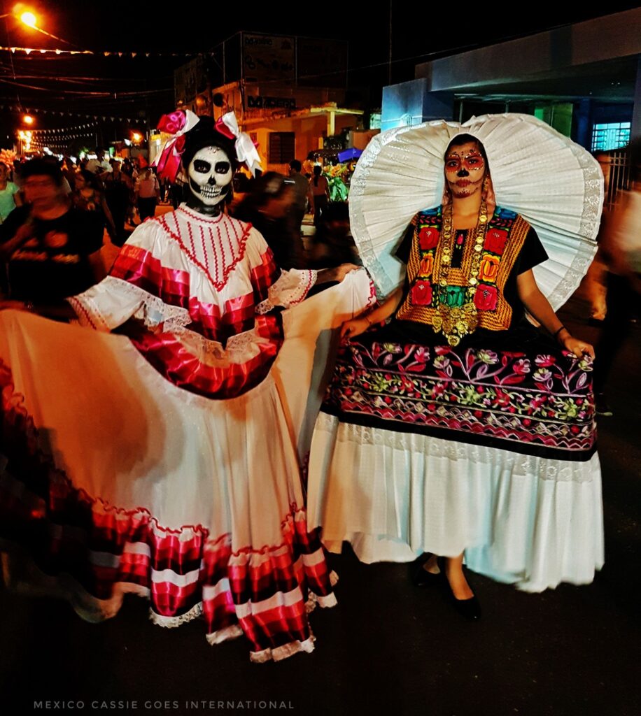 two women with faces painted for day of the dead in traditional mexican dress