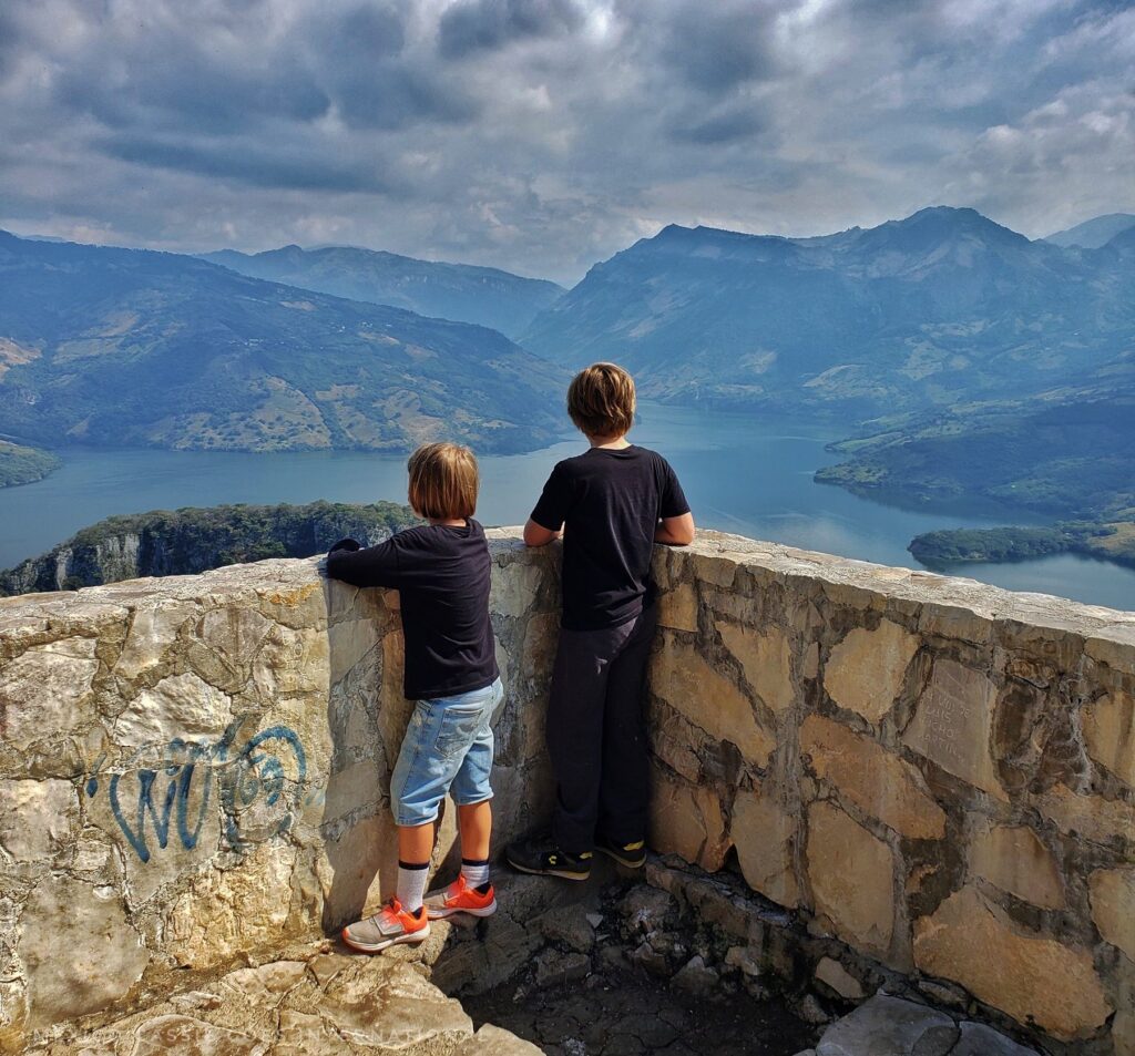 2 children standing leaning against a wall looking out over incredible river views
