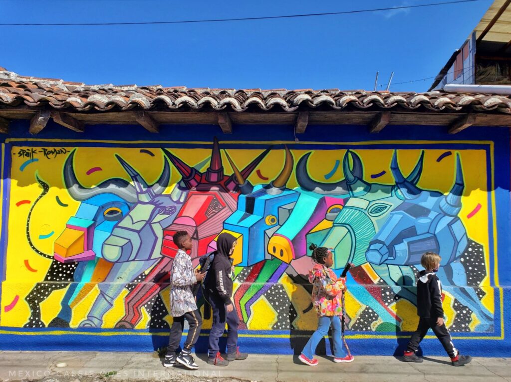 four children in height order walking in front of a mural of modern looking bulls