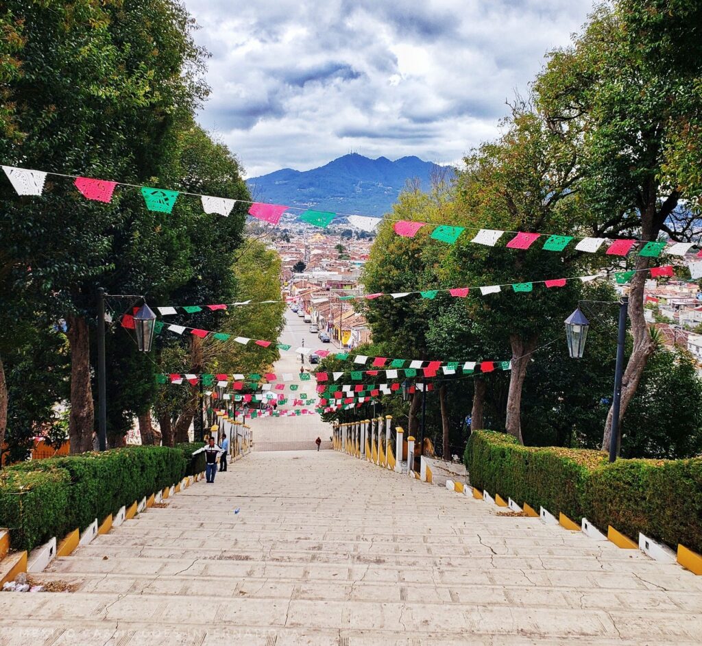 view down a large set of steps, red, green and white pennants flying, mountain in background