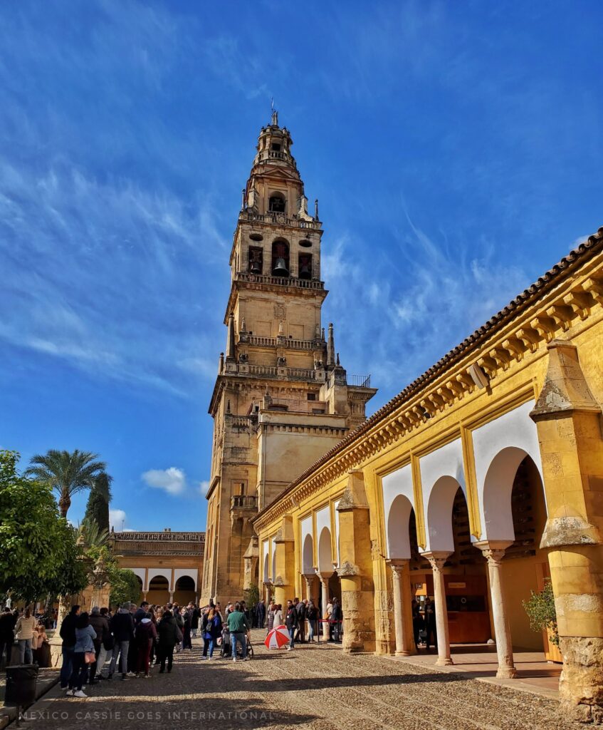 view of the cordoba bell tower  blue sky, people standing on left in shade