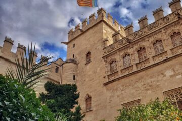 view of a corner of a castle looking building with a flag flying and orange trees all around