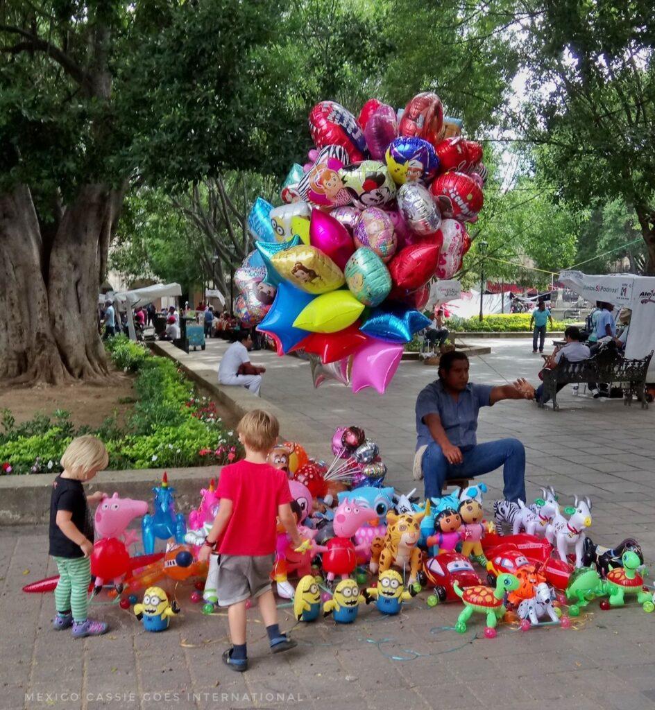 small children looking at street seller who has balloons and plastic toys