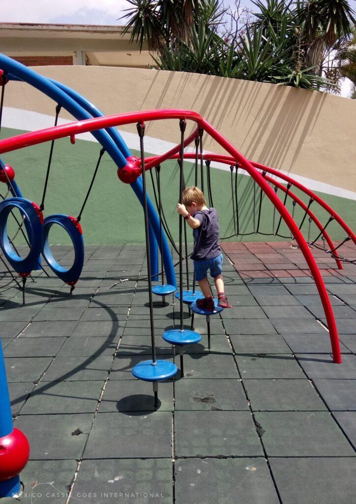 small child playing on a blue and red climbing frame