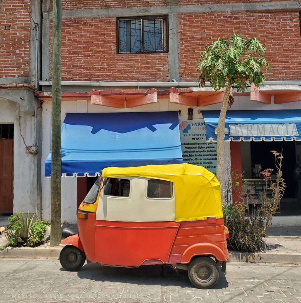 red and yellow tuktuk outside shop with blue awning