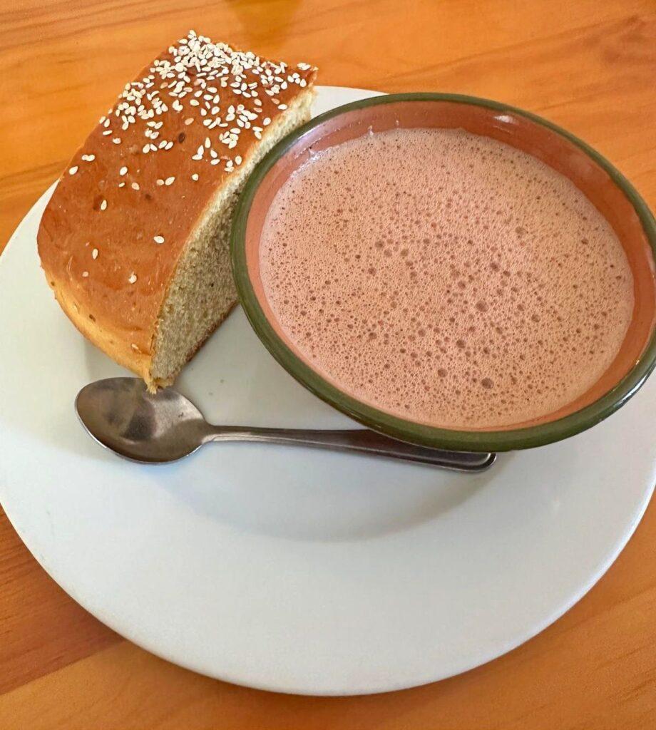 traditional oaxacan hot chocolate in a cup  with a piece of bread with sesame seeds on top