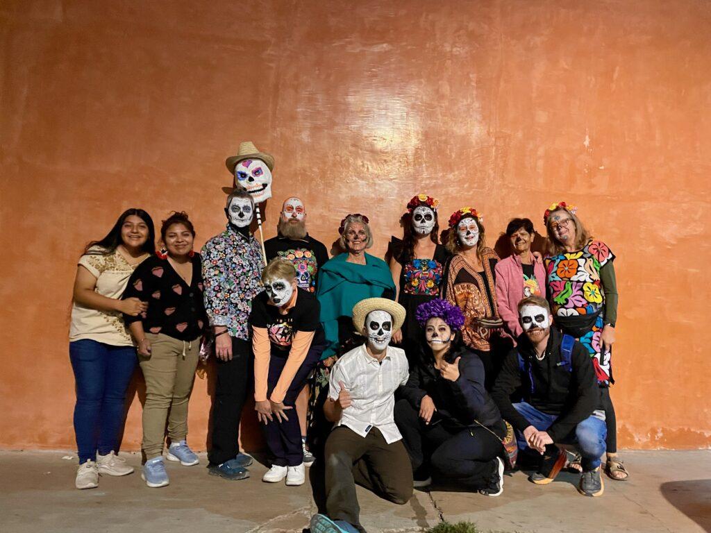 group of people against a wall - everyone has their faces painted for day of the dead