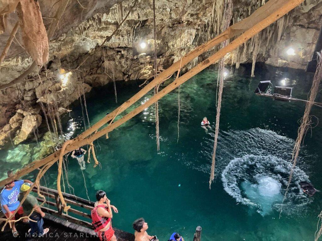 looking down on a cenote from above, circular splash where someone has just entered the water