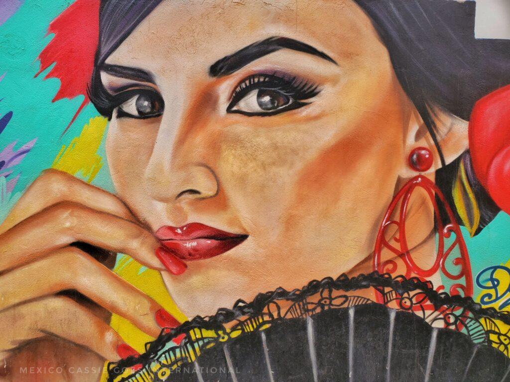street art of a Spanish woman's face - holding a lace fan, big red earring and red finger nails