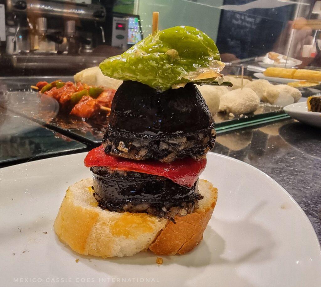 a piece of bread piled high with morcilla and peppers