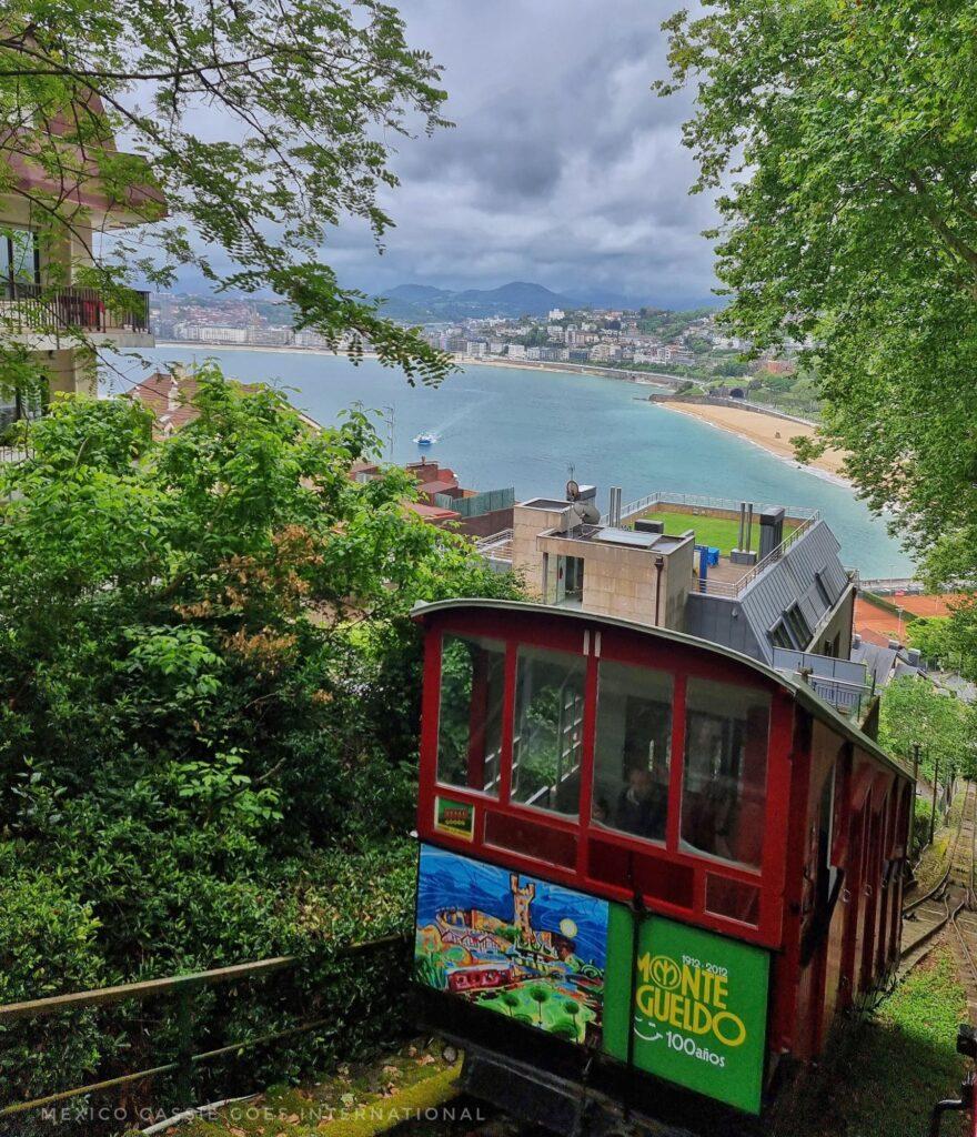 red funicular on track with beach and trees behind