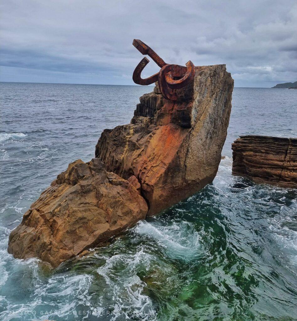 piece of steel sticking out of a rock in the ocean (peine del viento sculpture)